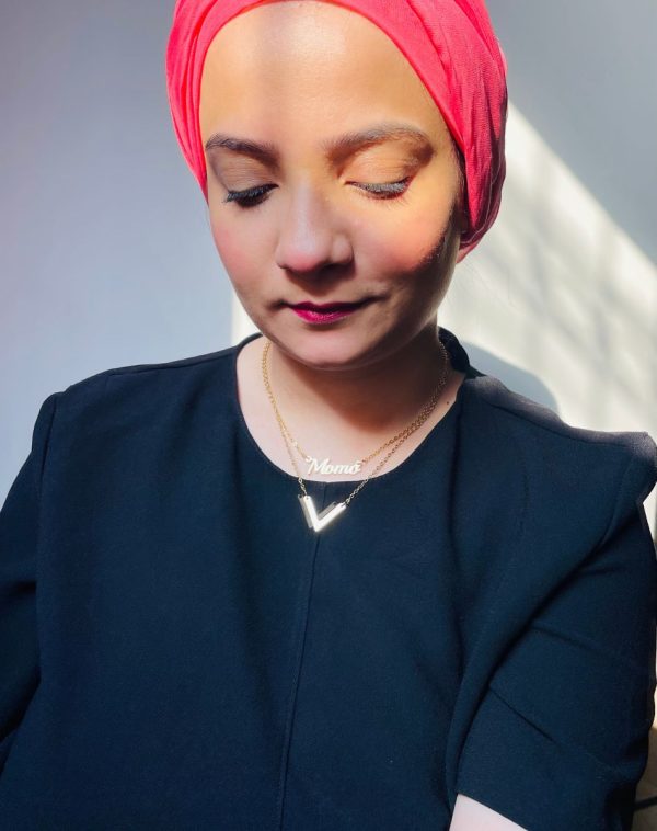 lose-up selfie of influencer Momo wearing our customized Double Chain Single Name Gold-Plated Necklace, with a pink scarf against a plain background in natural light.