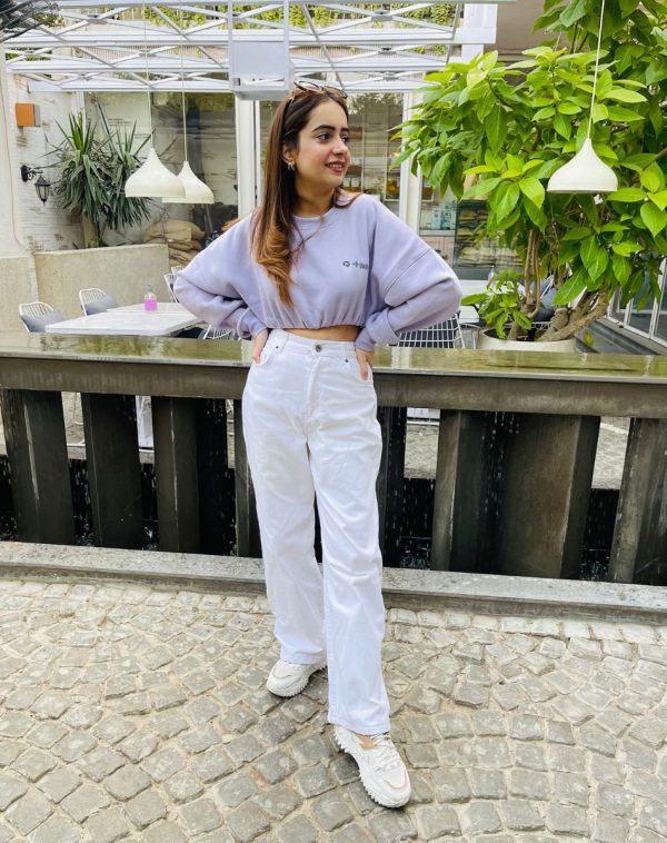 Full-length view of Lilac Cropped Drop Shoulder Scannable Sweatshirt in the highest quality fleece material. Palvi Ramani strikes a stylish pose, showcasing the trendsetting sweatshirt with a complete look, including joggers. Ideal women's fashion for casual elegance.