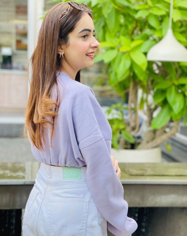 Close-up detail of Lilac Cropped Drop Shoulder Scannable Sweatshirt, showcasing the highest quality fleece material. Palvi Ramani's side pose highlights the intricate design of the product.