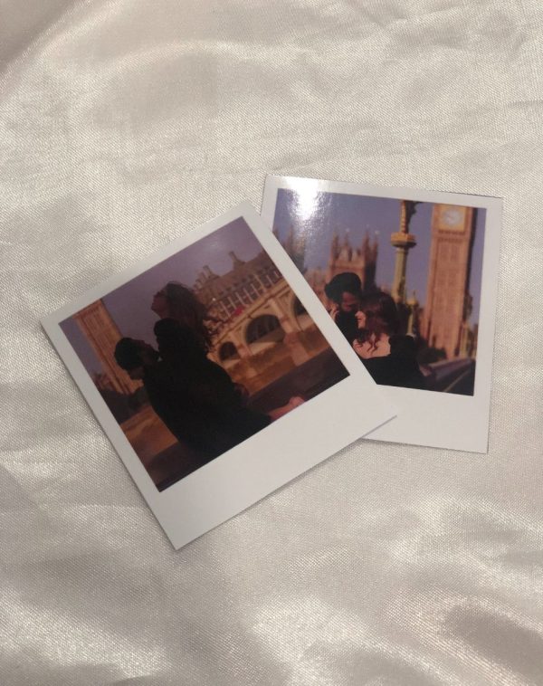 Two Polaroid pictures resting on a white bed, instant photography, cherished memories, vintage vibes, J's Store.