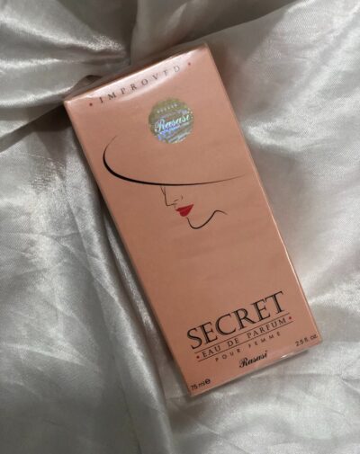 Rasasi Secret Eau De Parfum 75ml in a soft peach packaging placed on a silver satin fabric