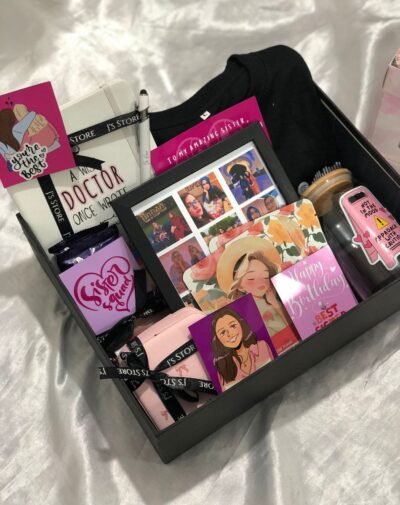 The Custom 'It Girl' Box is a large white gift box showcasing the customized contents like a journal, tumbler, and photo frame.