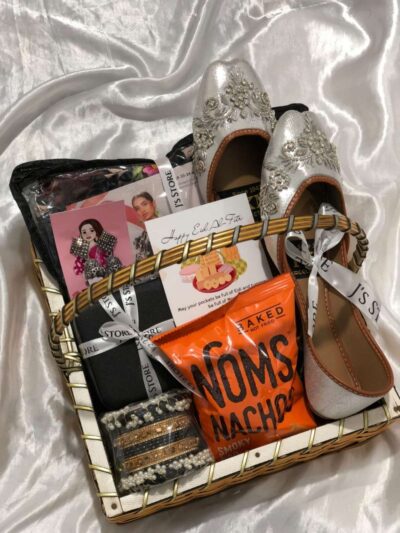 The Festive Muse Basket is a premium Eid Gift Baskets For Her from J’s Store featuring an unstitched suit, khussa, and jewelry.